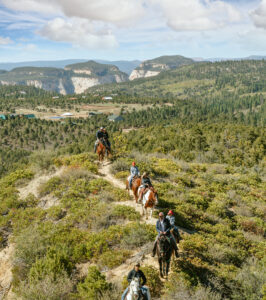 A group of people riding on horseback across trails from Zion Ponderosa Ranch & Resort to Zion National Park